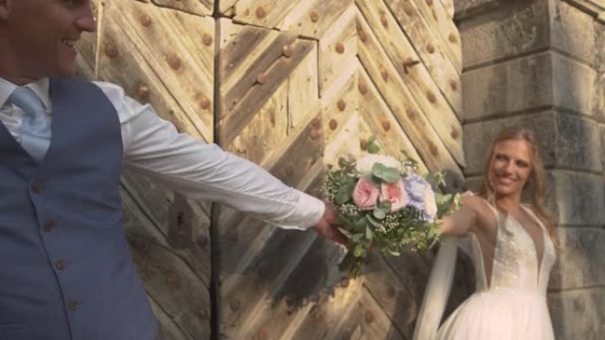在木门上关闭快乐的新婚夫妇，摆着美丽的新娘花束