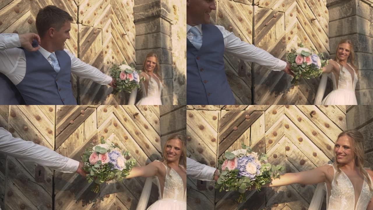 在木门上关闭快乐的新婚夫妇，摆着美丽的新娘花束