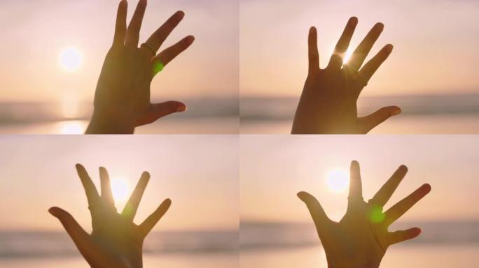 近距离女子手伸向阳光在沙滩上玩金色光线在日落