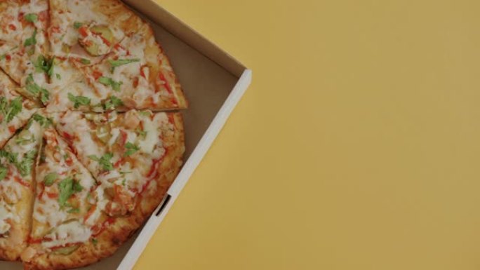 黄色背景下装在纸盒里的美味披萨的特写