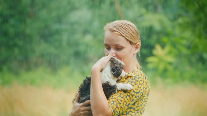 穿着夏装的湿女人在温暖的雨中抱着一只小狗