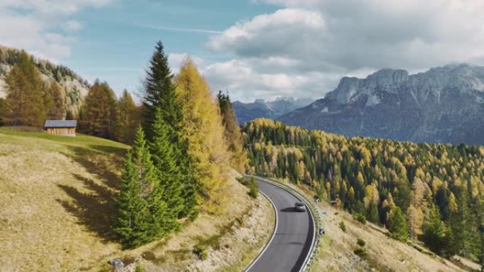 秋天穿越阿尔卑斯山的蜿蜒道路上的汽车鸟瞰图