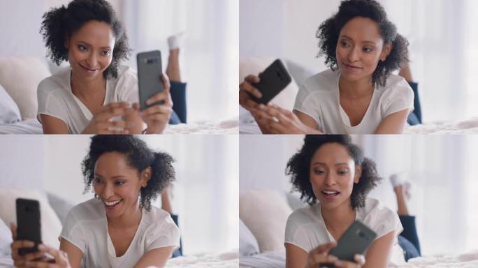 美丽的女人使用智能手机拍摄自拍照片，享受在社交媒体上分享生活方式躺在家里的床上
