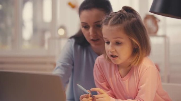 微笑的女人和小女儿在笔记本电脑上做作业，在线教育