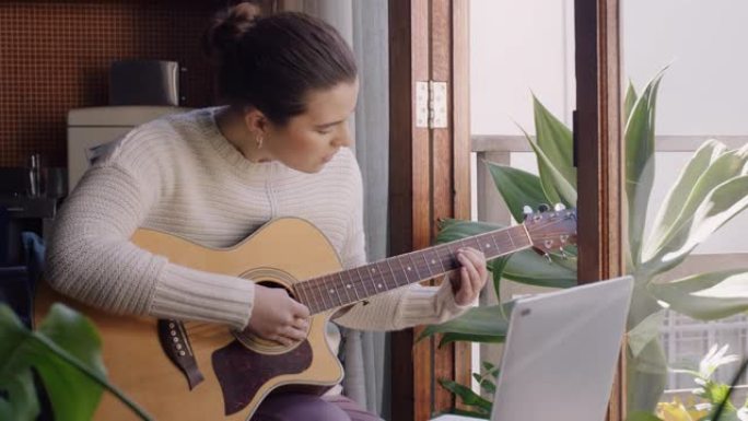 年轻女子在家弹吉他有抱负的音乐家学习用笔记本电脑演奏乐器享受创造性表达练习音乐