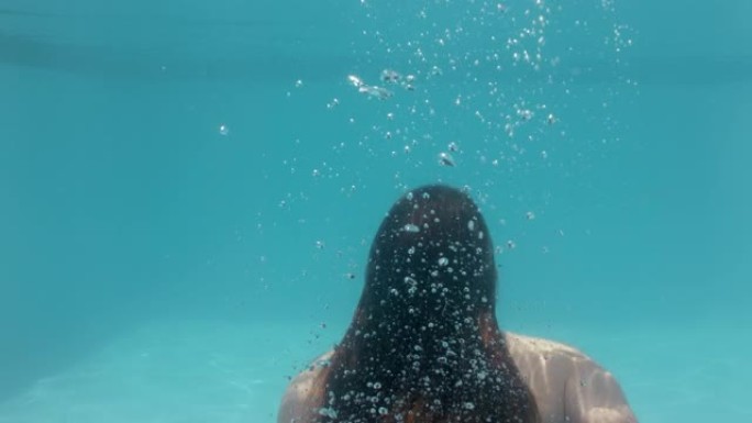 美丽的女人在游泳池水下游泳漂浮在蓝色水晶清澈的水中，夏天穿着性感的红色泳衣4k，玩得开心