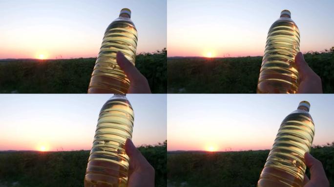 一瓶葵花籽油在田野里美丽的日落。葵花籽油广告。