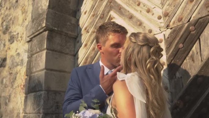 特写: 浪漫的新婚夫妇在木门前分享一个充满爱意的吻