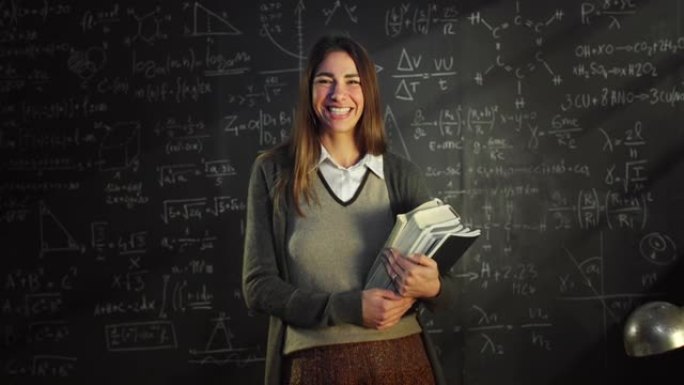 放大: 大学教室里年轻女教师的肖像站在黑板前，用数学公式。大学图书馆的科学女研究员，看着相机，微笑着