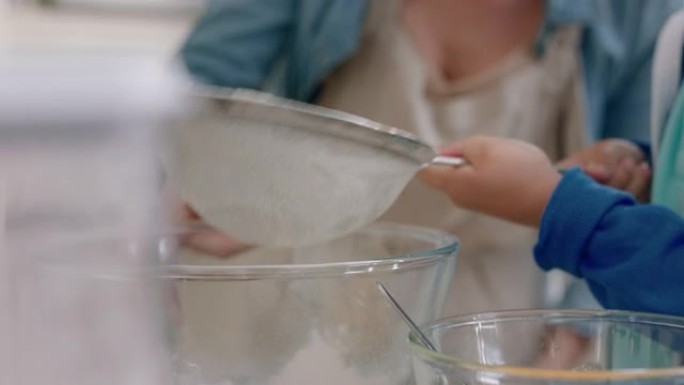 小男孩帮助母亲在厨房里烘烤混合配料用筛子筛分面粉在家准备纸杯蛋糕的配方