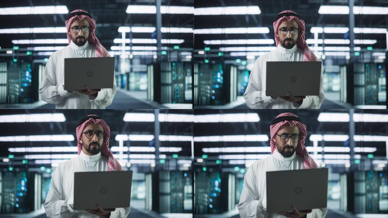 穆斯林数据中心技术经理的肖像穿着传统的白色衣服，在现代技术服务器农场设施中使用笔记本电脑。工作中的阿