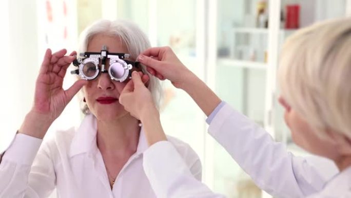 眼科医生戴眼镜检查视力并为诊所的老年妇女患者配戴眼镜4k电影慢动作