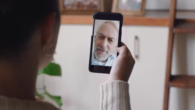 年轻女子使用智能手机进行视频聊天，与祖父聊天，享受对话分享生活方式与家里的手机交流