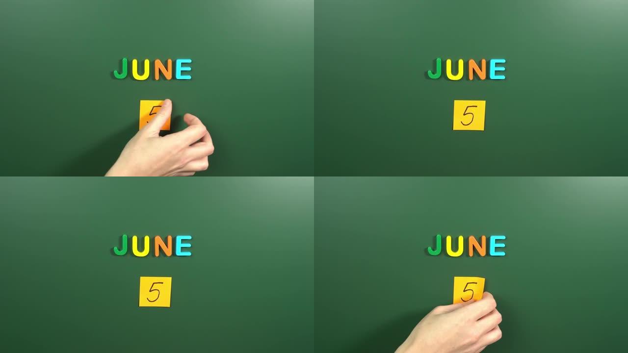 6月5日日历日用手在学校董事会上贴一张贴纸。5 6月日期。6月的第五天。第5个日期号。5天日历。五次