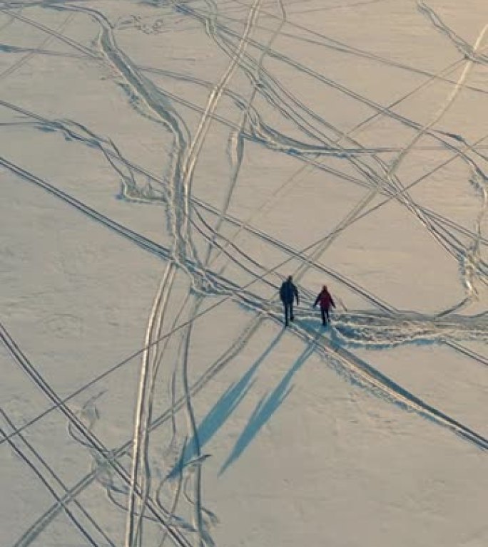 两个背着背包的旅行者穿过雪场