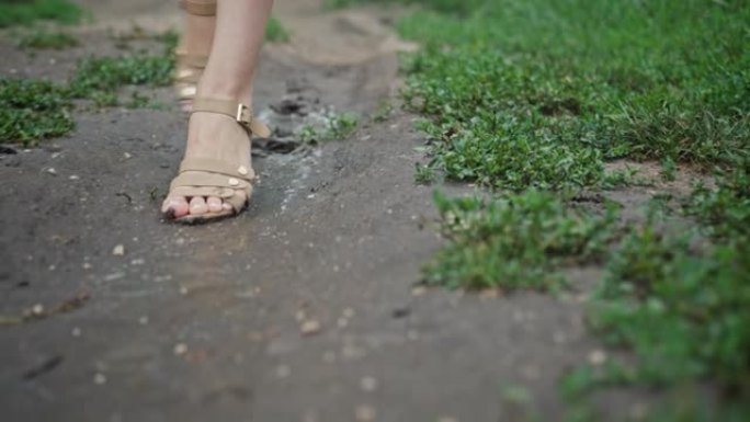 女性穿着高跟凉鞋走在泥泞的小路上