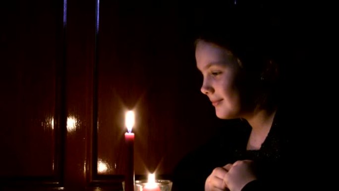 女孩少年看着一支燃烧的蜡烛。