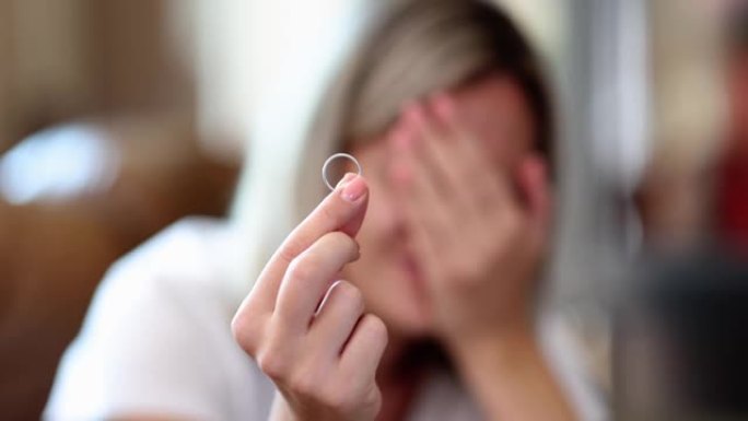 女人哭着拿着订婚戒指用手遮住脸