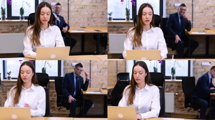 实时视频。两个白人同事男人和女人在办公室工作。女性正在笔记本电脑上打字，男性将纸飞机降落在桌子上。