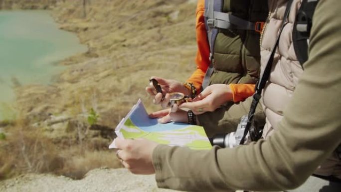 两名游客在岩石湖海岸学习地图和指南针的中段拍摄