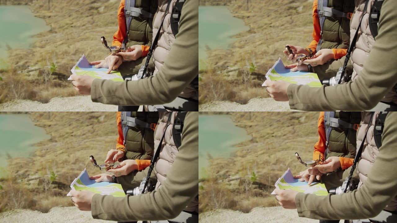 两名游客在岩石湖海岸学习地图和指南针的中段拍摄