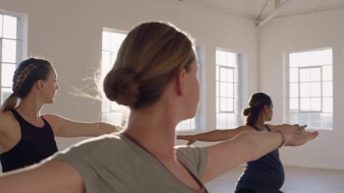 日出时在工作室与教练一起练习战士姿势的健康孕妇瑜伽课享受团体体能锻炼