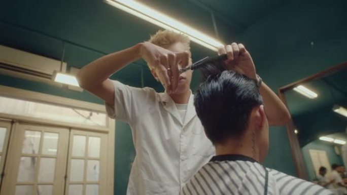 亚洲理发师在理发店稀疏客户的头发