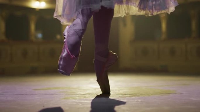 穿着脚尖鞋的芭蕾舞女演员脚的特写镜头和白色芭蕾舞短裙在剧院舞台上优雅地跳舞，并带有戏剧性的灯光。女古