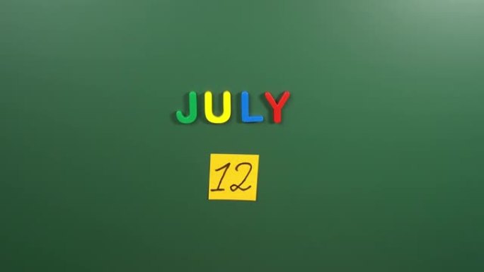 7月12日日历日用手在学校董事会上贴一张贴纸。12 7月日期。7月的第十二天。第12个日期编号。12