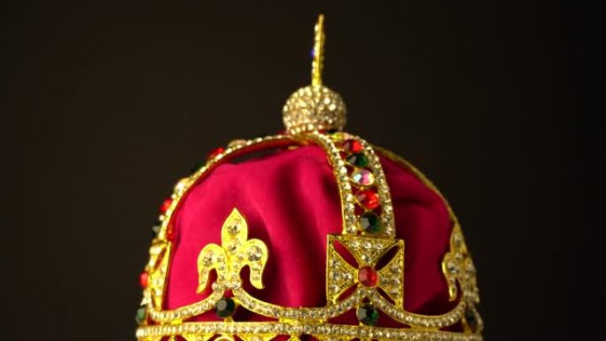 金色和红色皇家柔软天鹅绒材料制成的钻石皇冠，用于黑色背景上的加冕礼。在慢速旋转运动中，焦点集中在框架
