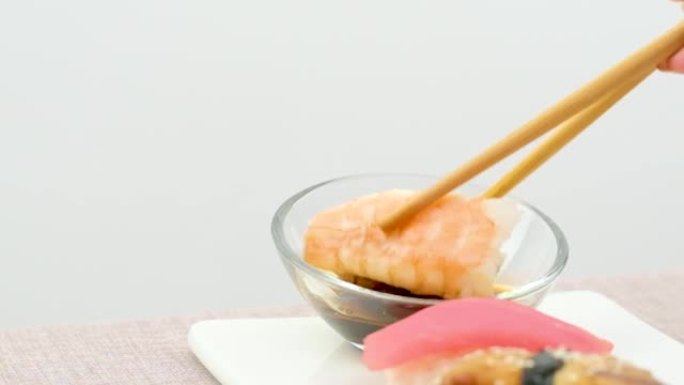 学习如何用筷子蘸寿司失败尝试一块带鱼的米饭掉进盘子里把酱油洒在白色背景上特写初学者学会用筷子吃饭