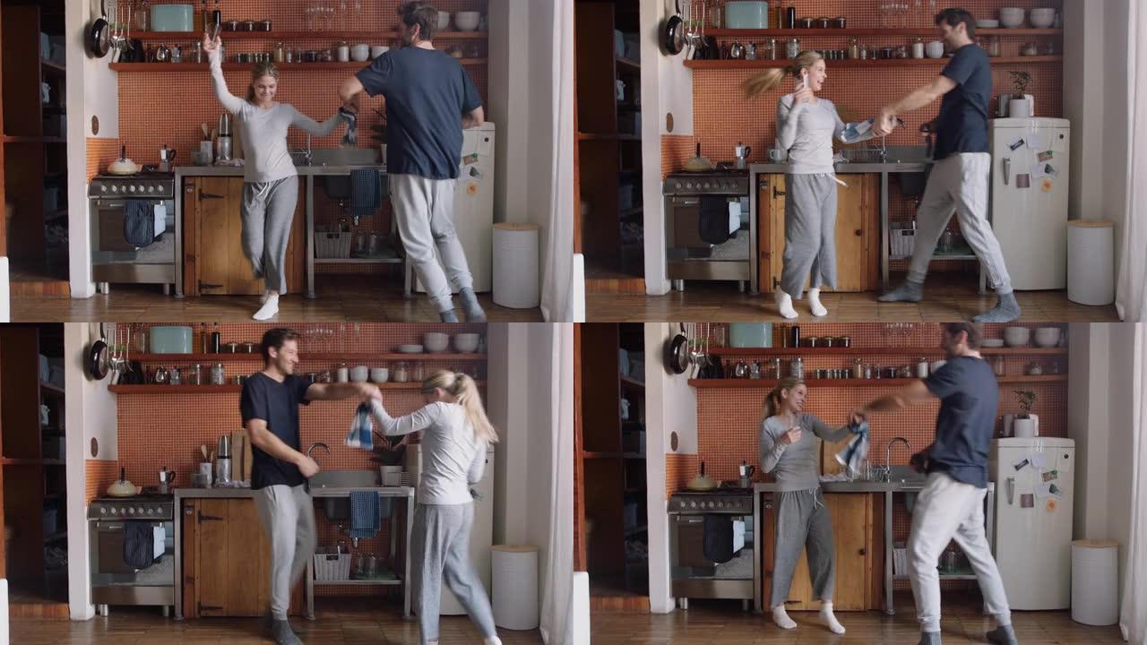 快乐的年轻夫妇在厨房跳舞，一起享受有趣的舞蹈，周末在家庆祝关系