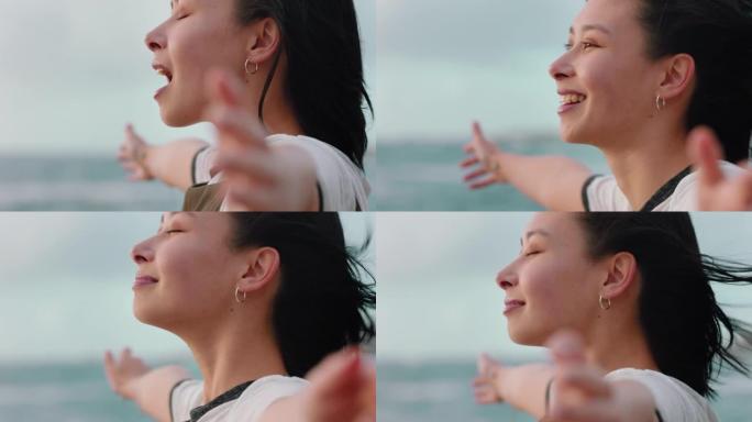 快乐的亚洲妇女享受自由的肖像，手臂举起，在日落的海滩上感受快乐，在风吹拂的头发中探索旅行