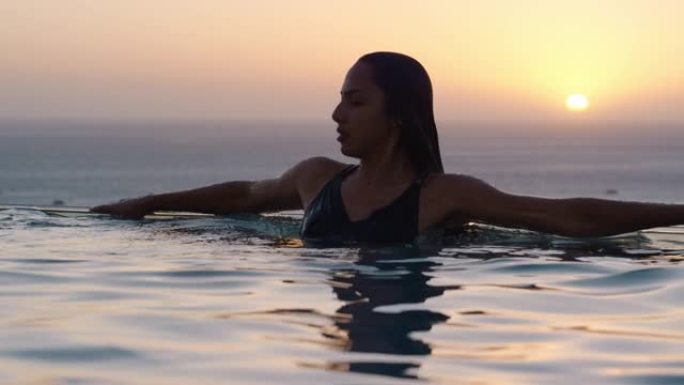 女子在泳池游泳在豪华酒店水疗中心与美丽的日落海景地中海旅游度假胜地放松的生活方式自由4k