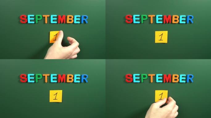 9月1日日历日用手在学校董事会上贴一张贴纸。1 9月日期。9月的第一天。第一个日期号。1天日历。一次