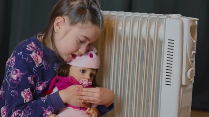 欧式房间电暖器散热器附近的冷女孩与娃娃玩具取暖发抖