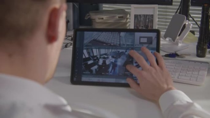 保安在平板电脑上监控闭路电视摄像头