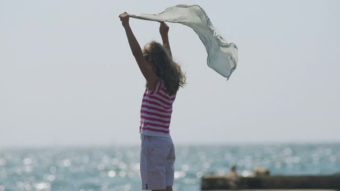 Slow-Mo: 快乐的女孩在海上顶风拿着丝绸围巾