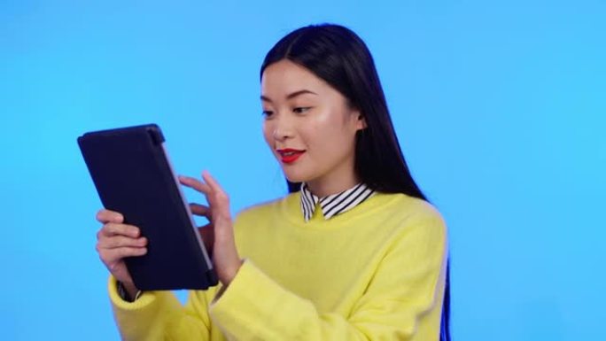 亚洲女性，平板电脑和工作室，用于交流，互联网和社交媒体的蓝色背景。移动应用程序上的快乐模特在线聊天，