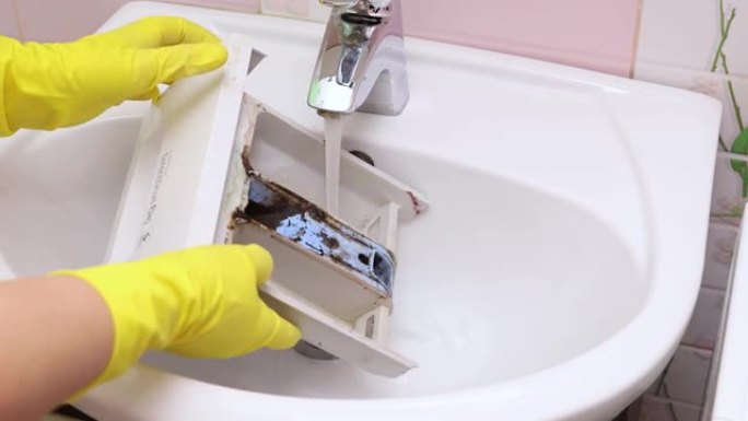 女性用自来水冲洗洗衣机粉末容器。从里面的深色霉菌中清洁容器。