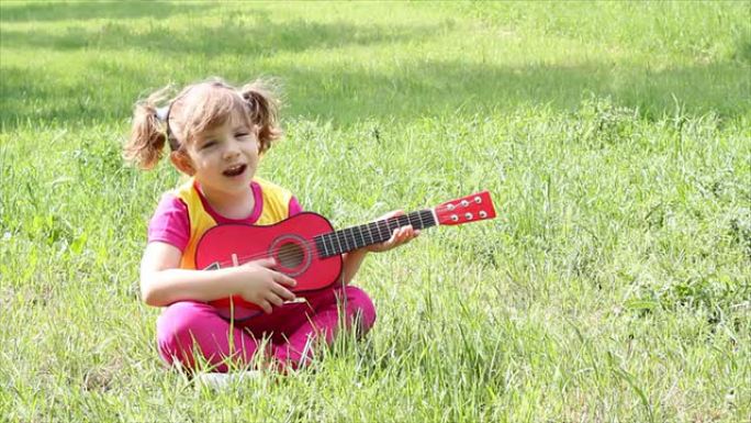 小女孩坐在草地上弹吉他