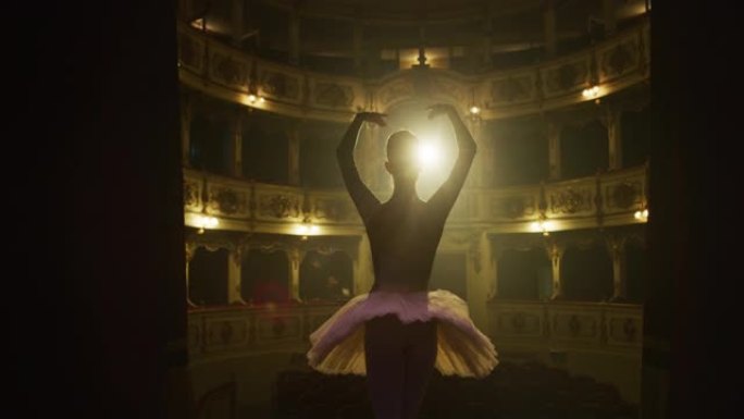 年轻的古典芭蕾舞女舞者站在经典剧院舞台上的电影背景图，聚光灯下进行谢幕。优雅的表演者接受观众对她的才