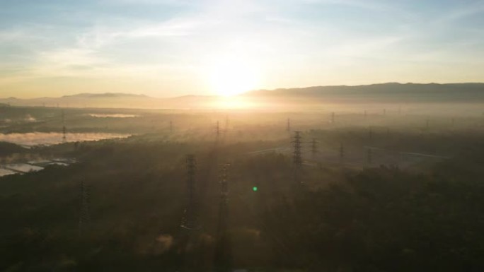日出时高压电力塔架剪影的航拍