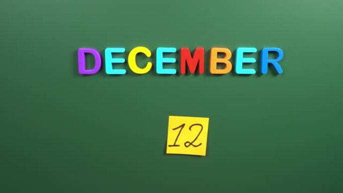 12月12日日历日用手在学校董事会上贴一张贴纸。12 12月日期。12月的第十二天。第12个日期编号