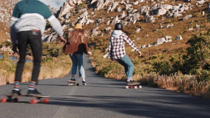 年轻的多民族朋友一起骑滑板在乡村道路上下坡巡航，享受轻松的暑假