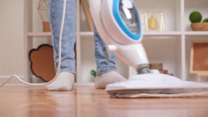 男子用蒸汽拖把洗地板。用热蒸汽进行地板处理。清洁卫生控制。
