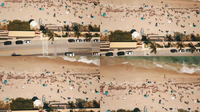 在春季休息2023中午，佛罗里达州棕榈滩的沙滩上，充满蓝色海浪、岩石、海藻、沙滩伞、冲浪板和人们的空