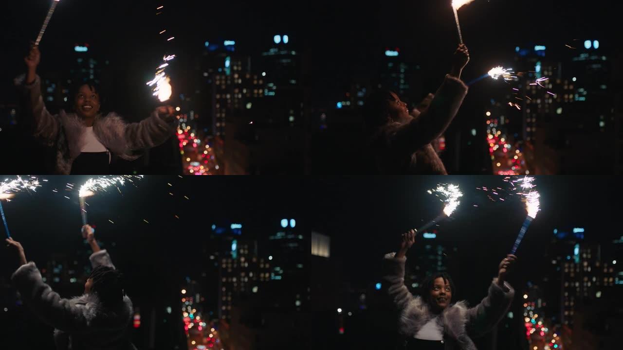 快乐的年轻非裔美国妇女拿着烟花在屋顶上跳舞，晚上庆祝新年除夕，享受节日庆祝活动
