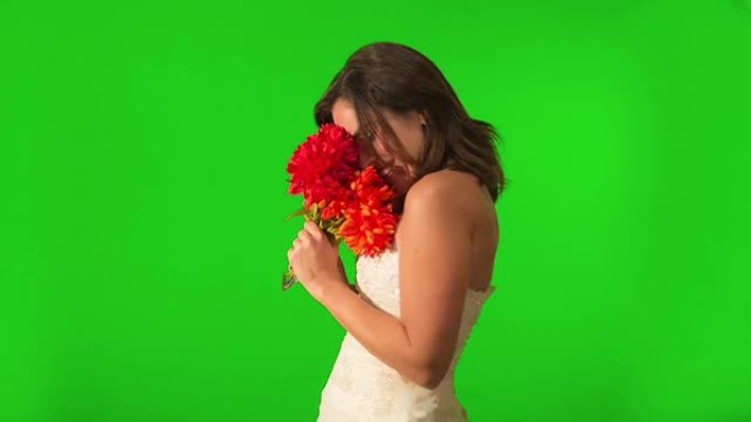 快乐的新娘看着她的戒指，拿着鲜花。在绿色屏幕上拍摄