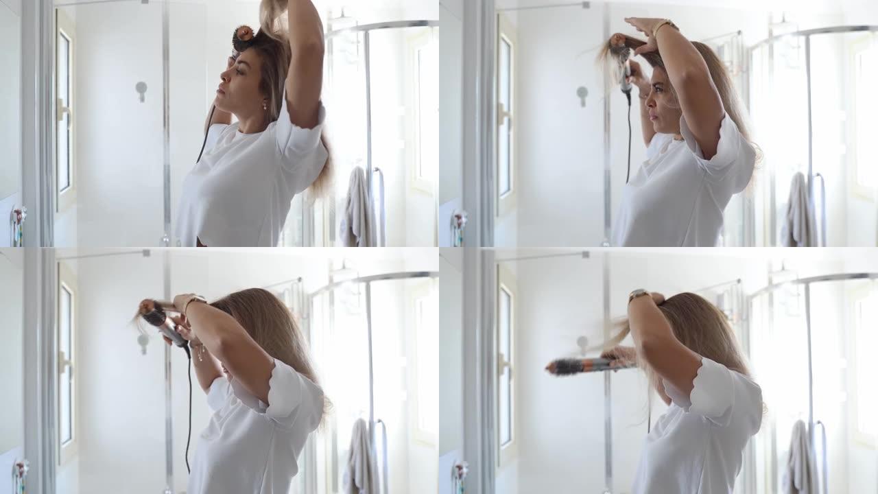 女人在浴室用吹风机造型护理机造型头发。年轻女性使用现代旋转发刷来定型头发。带附件的热和陶瓷涂层旋转刷